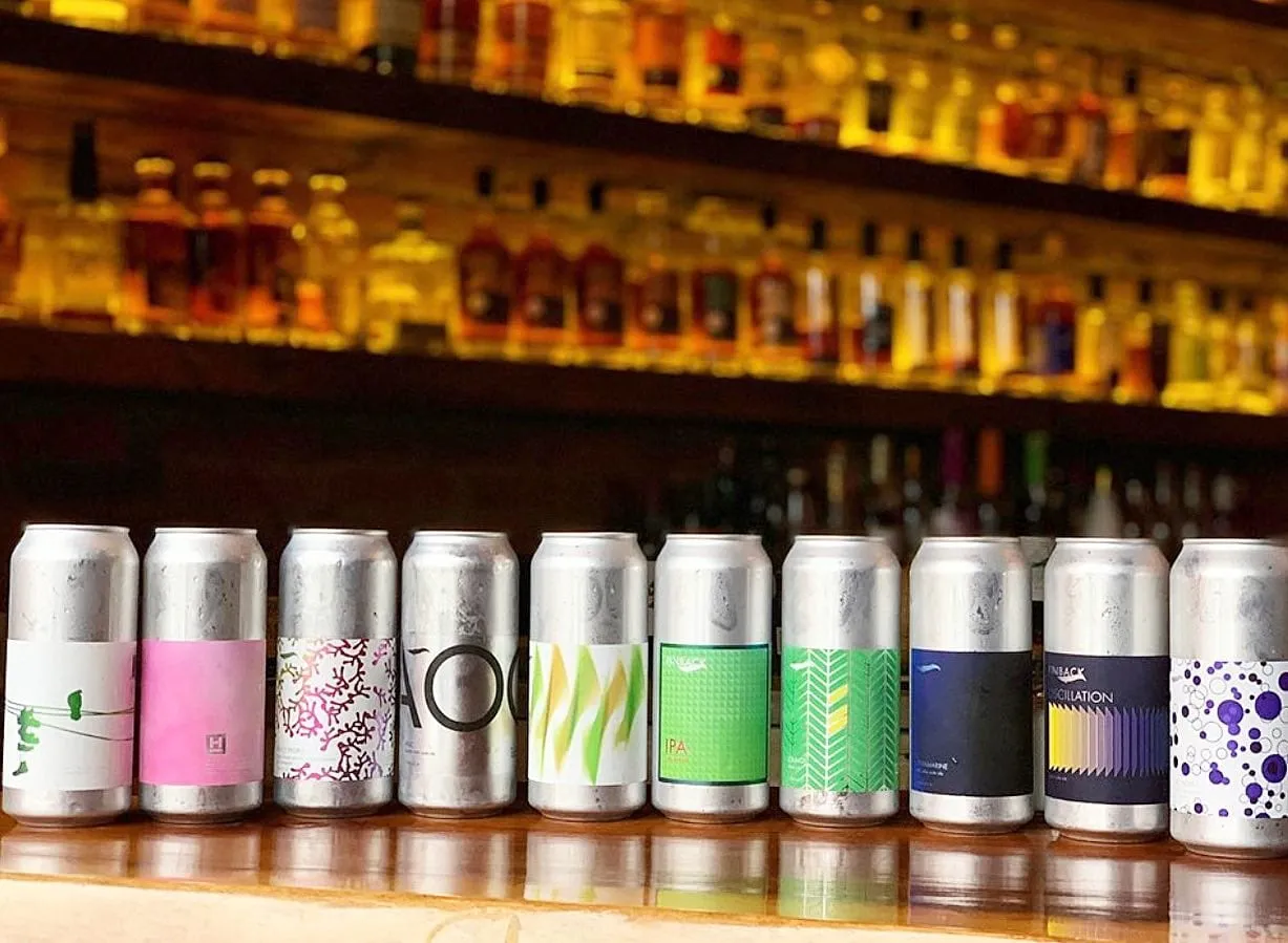 Craft cans lined up along the glowing back bar