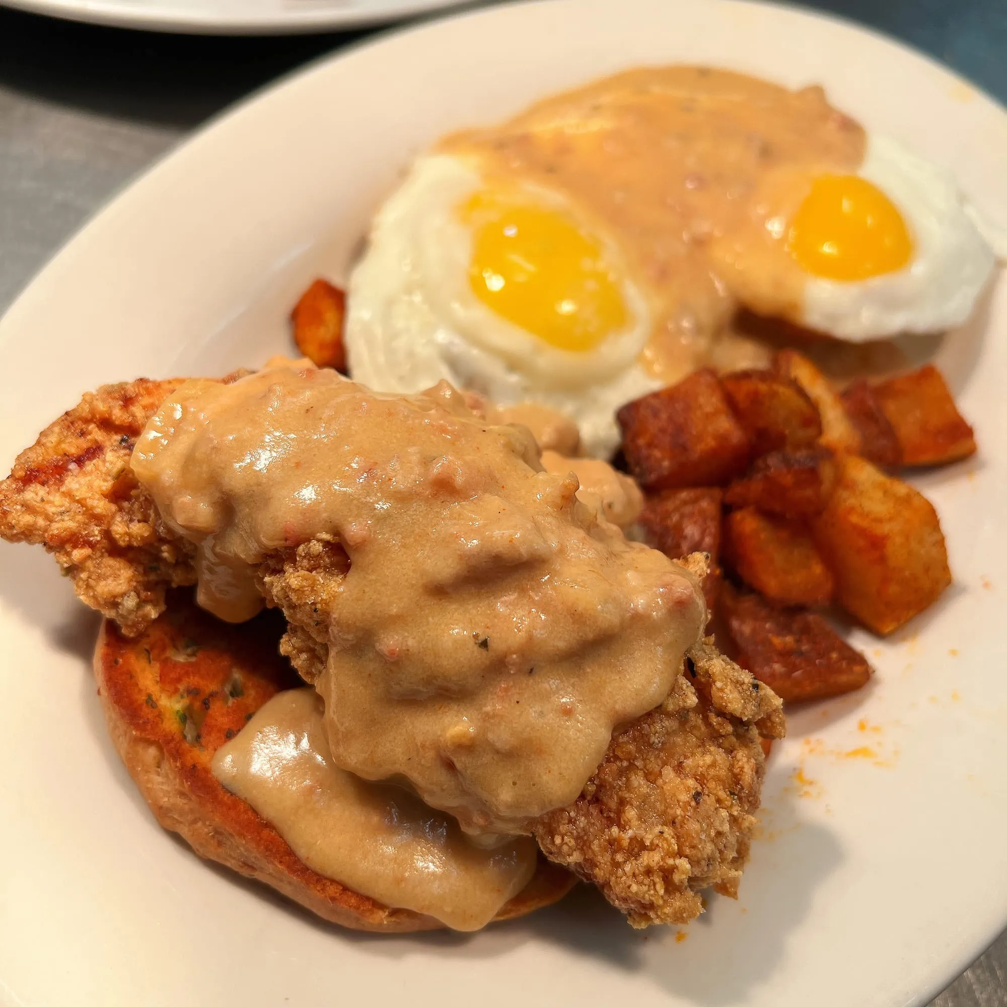 Fried chicken biscuit with sunny-side farm eggs and gravy
