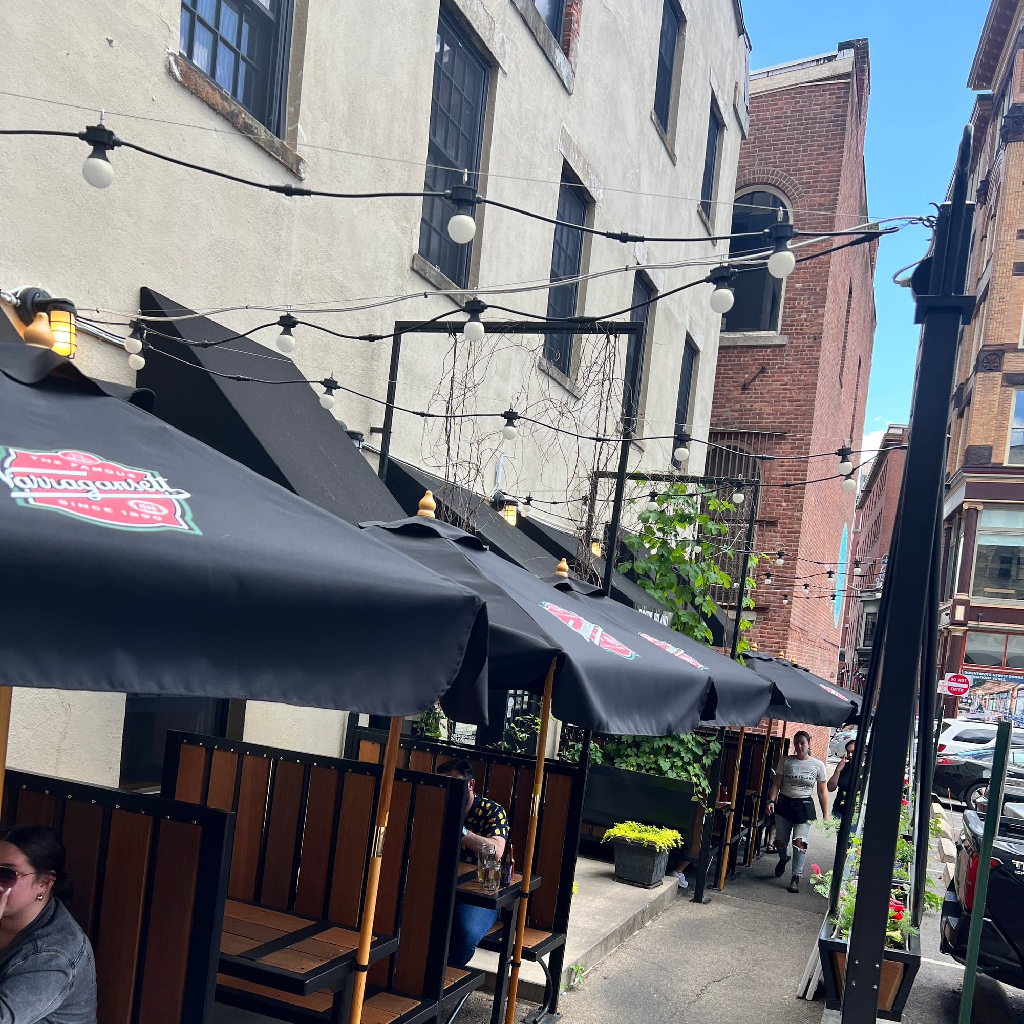 Summer on the Rogue Island patio — booth seating under Narragansett umbrellas and string lights